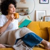 Girl on couch reading book and drinking coffee